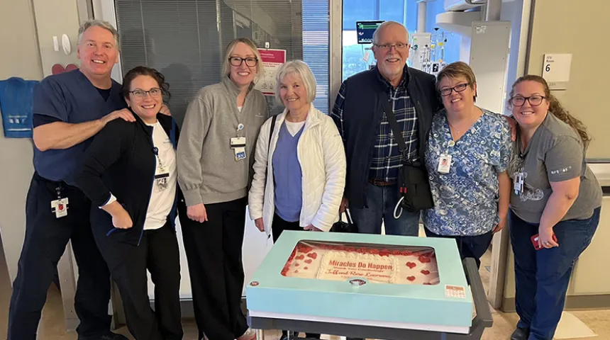 Donald "Jeff" Lawrence poses in front of the large cake he brought to visit the LVAD Program and cardiac care teams who helped him to recover after surgery.