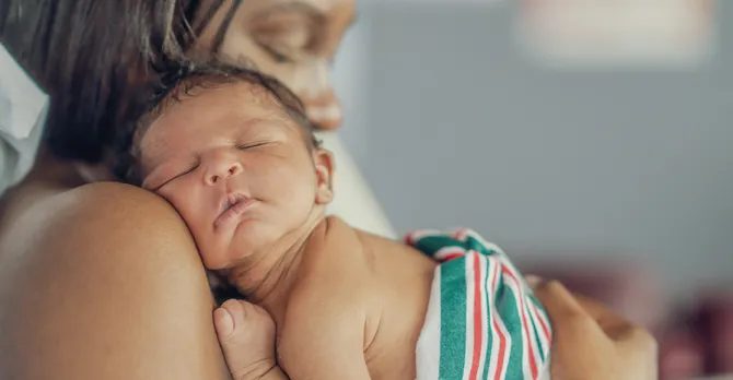 Young mom hugging her newborn baby after delivery.