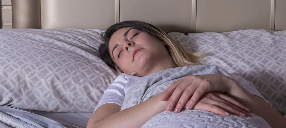 A woman sleeps on her back with help from mindfulness.