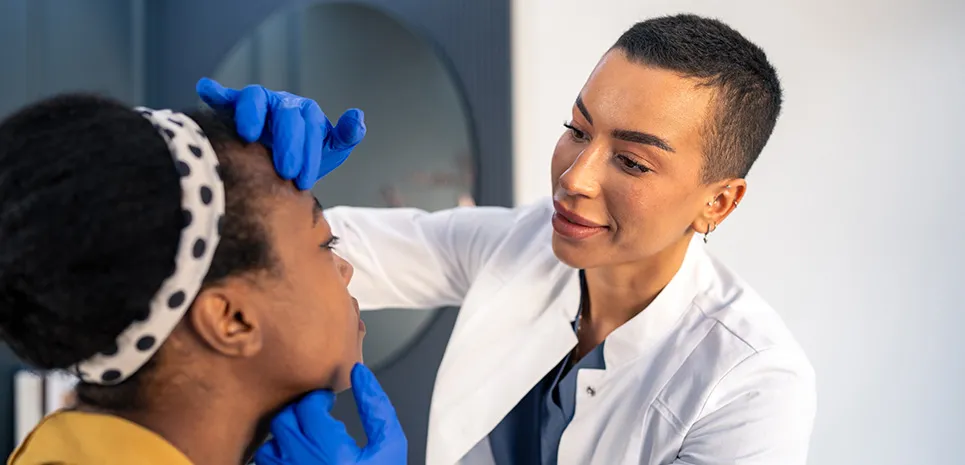A plastic surgeon examines the face of her patient.