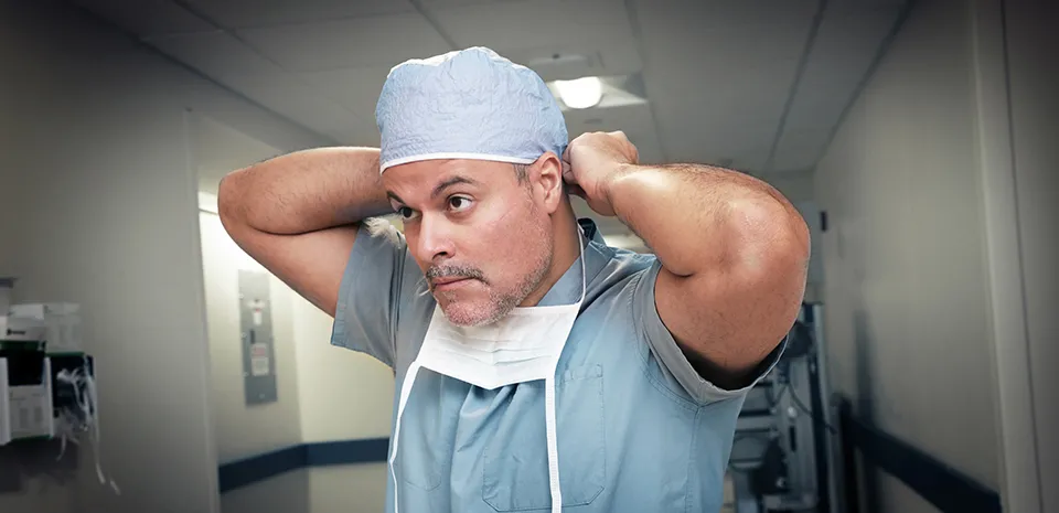 A caregiver putting on a mask and cap.