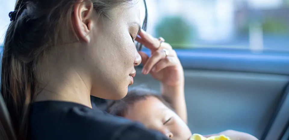 young mom experiencing postpartum depression while holding newborn baby
