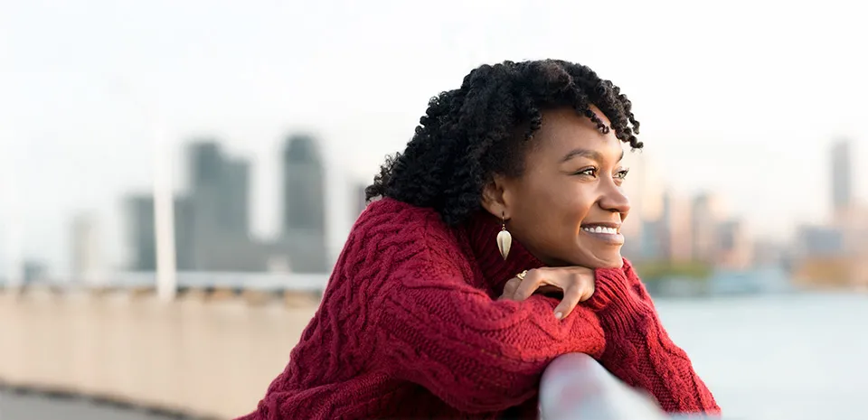 Woman looking over a bridge at the water and city