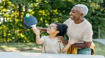 An older woman and a young girl enjoying a game of ping pong, highlighting their connection and shared fun.