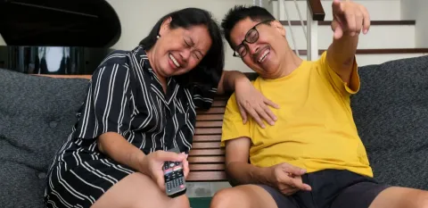 older couple watching TV and laughing which benefits heart health