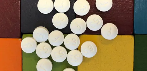 Multiple white pills are on top of different-colored blocks.