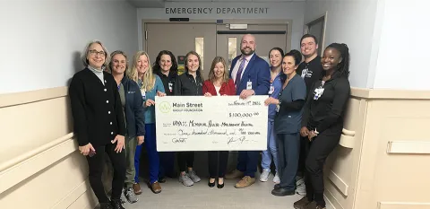 A group of caregivers at the Marlborough Campus hold up a large-size check from Community Bank in the amount of $100,000..