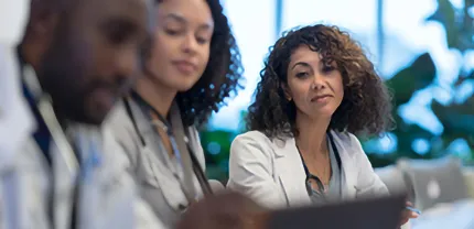 Three health care workers view a document together.