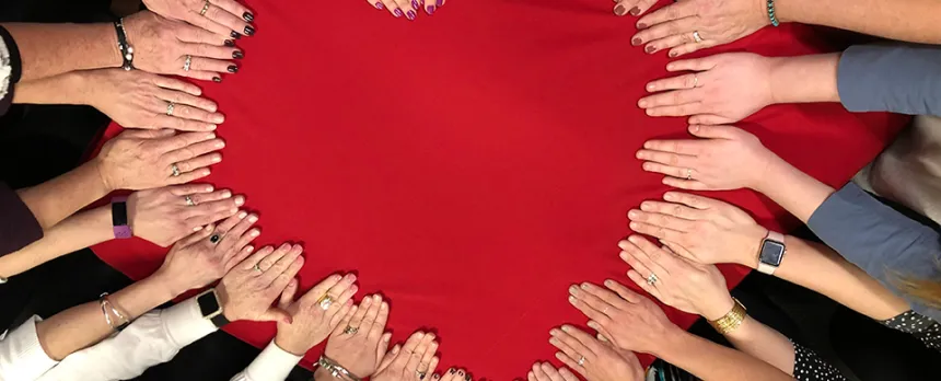 group of people putting hands together to shape a heart