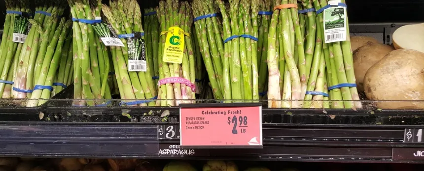 Bunches of asparagus are shown on a store shelf.