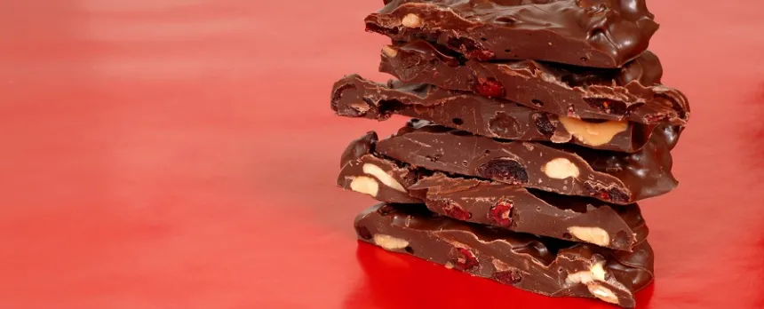 A stack of chocolate cherry bark is on a red table.