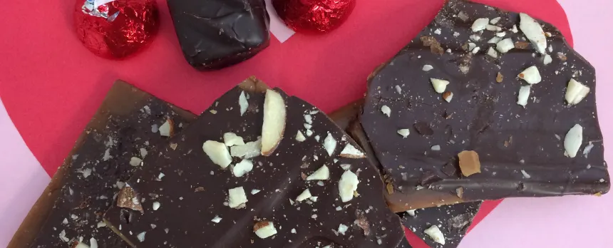 Chocolates and candies are shown on top of a red Valentine's heart.